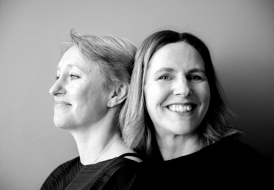 Två kvinnor som lutar sig mot varandra. Fotografi.