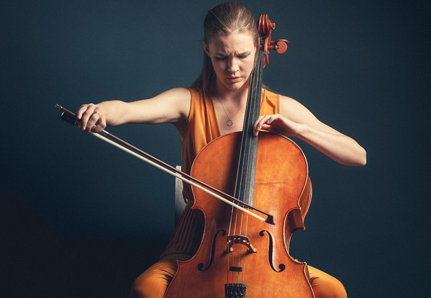 Närbild på ung kvinna som spelar cello. Fotografi.