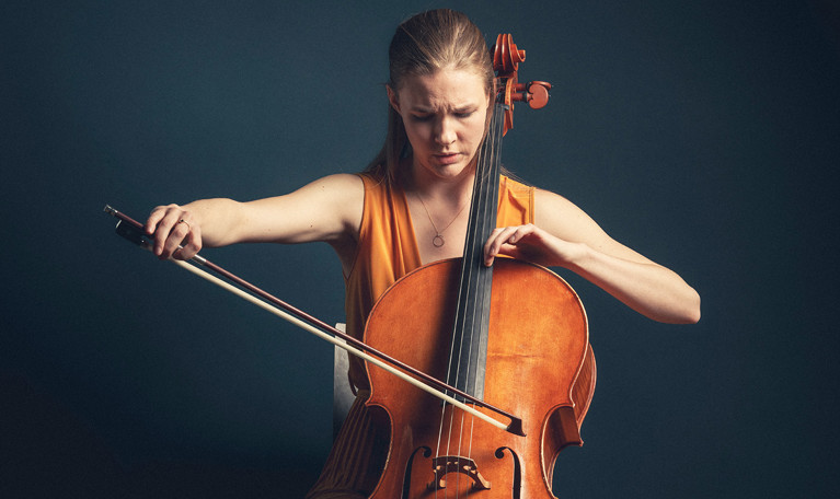 Närbild på ung kvinna som spelar cello. Fotografi.